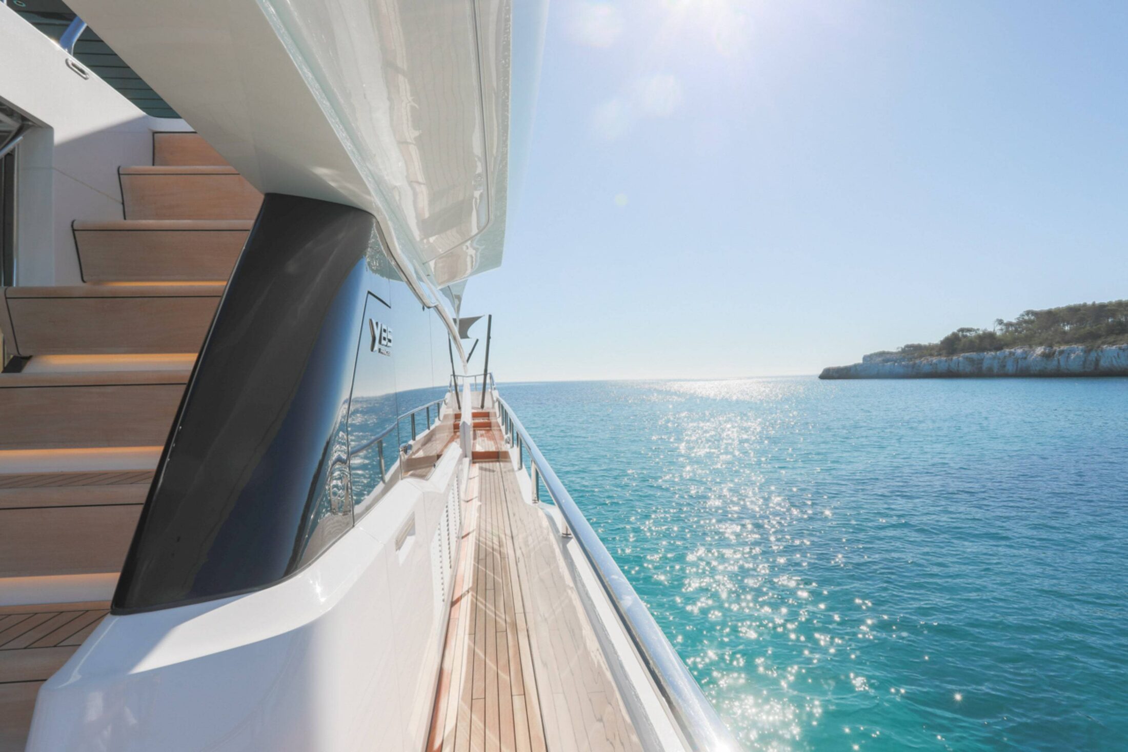 Superyacht side deck looking out over a sunlit bay